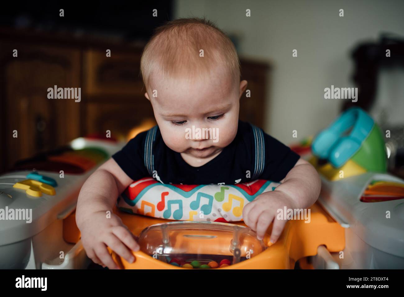Close up of baby boy standing in jumper playing with toy at home Stock Photo