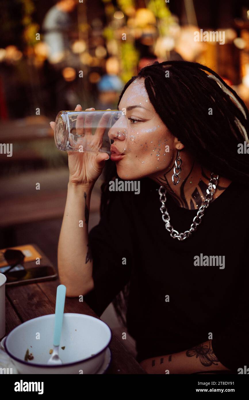 A young woman drinks from a glass in a cafe. Stock Photo