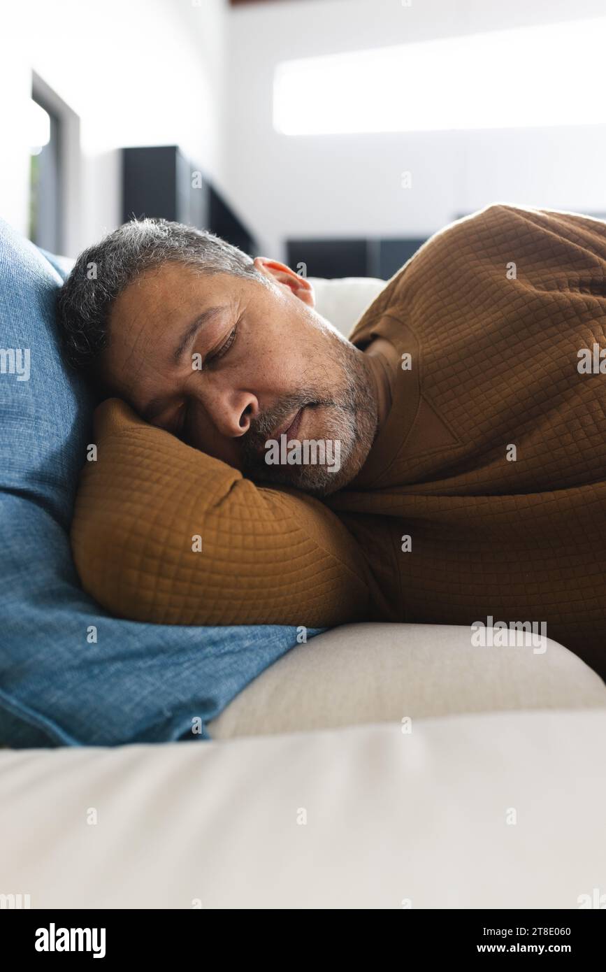 Senior biracial man lying on couch and sleeping at home Stock Photo