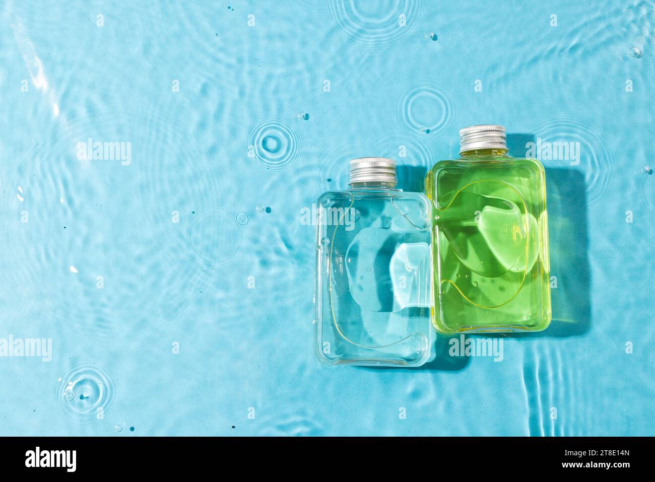 Beauty product bottles in water with copy space background on blue background Stock Photo