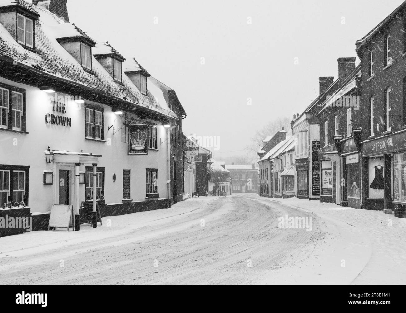 Falling snow on empty high street during 'Beast From The East' snowfall weather event in winter / spring 2018, UK. Black and white. Stock Photo