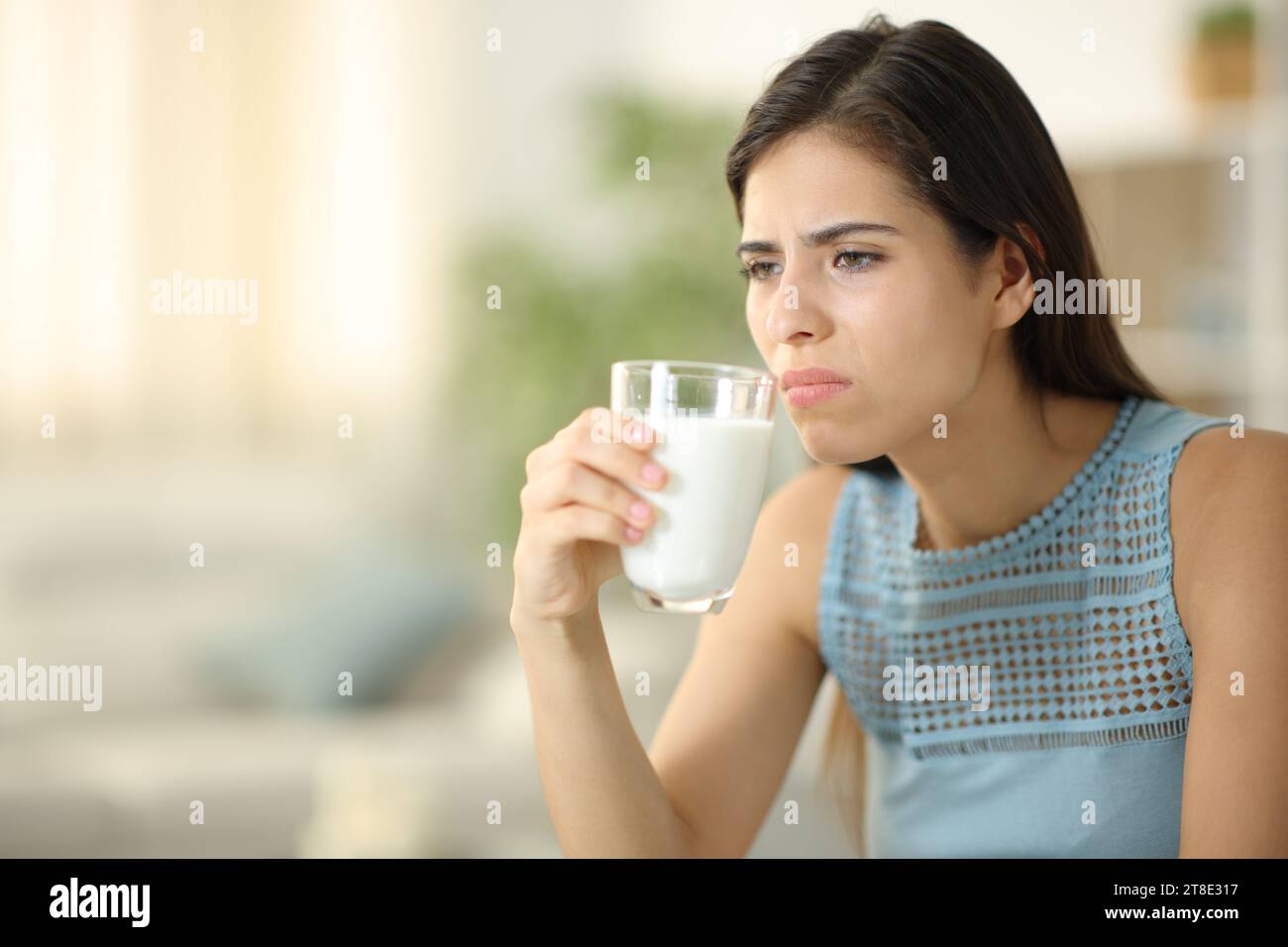 Disgusted woman smelling expired milk at home Stock Photo