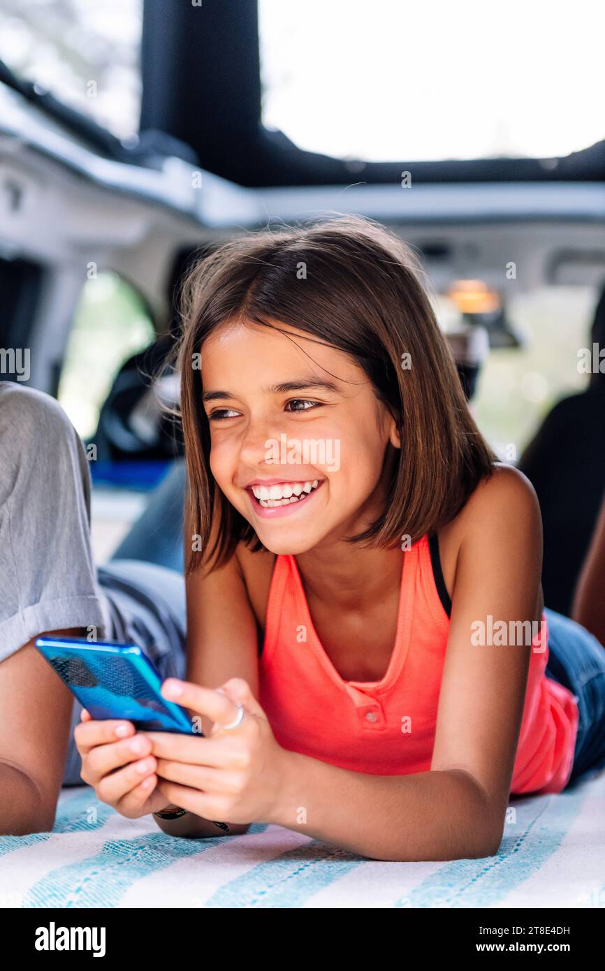 girl smiling using mobile phone in a camper van Stock Photo