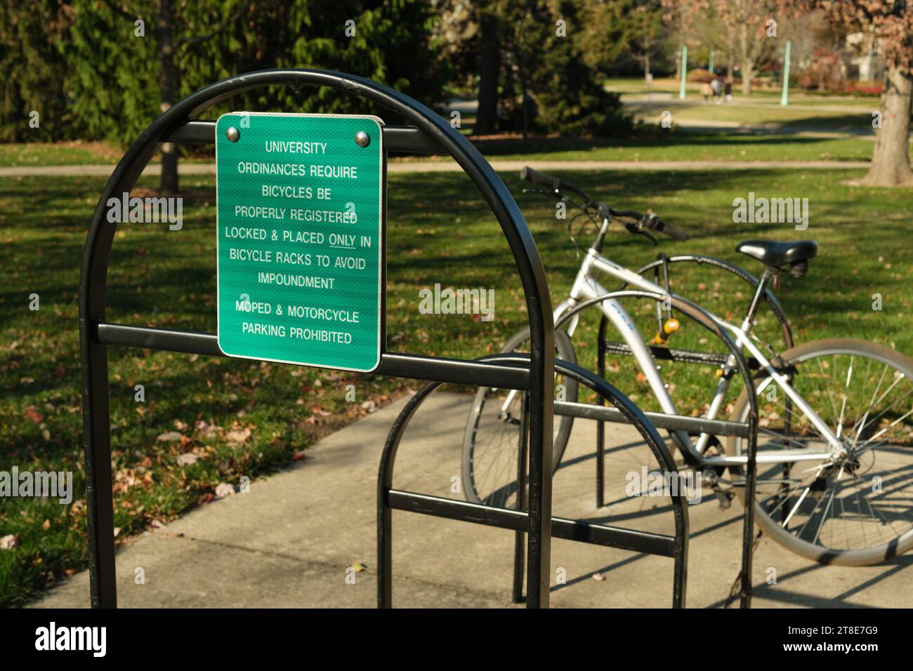 Bicycle and bike rack with sign warning that bikes are to be registered, placed in bike rack, and locked to avoid impoundment Stock Photo