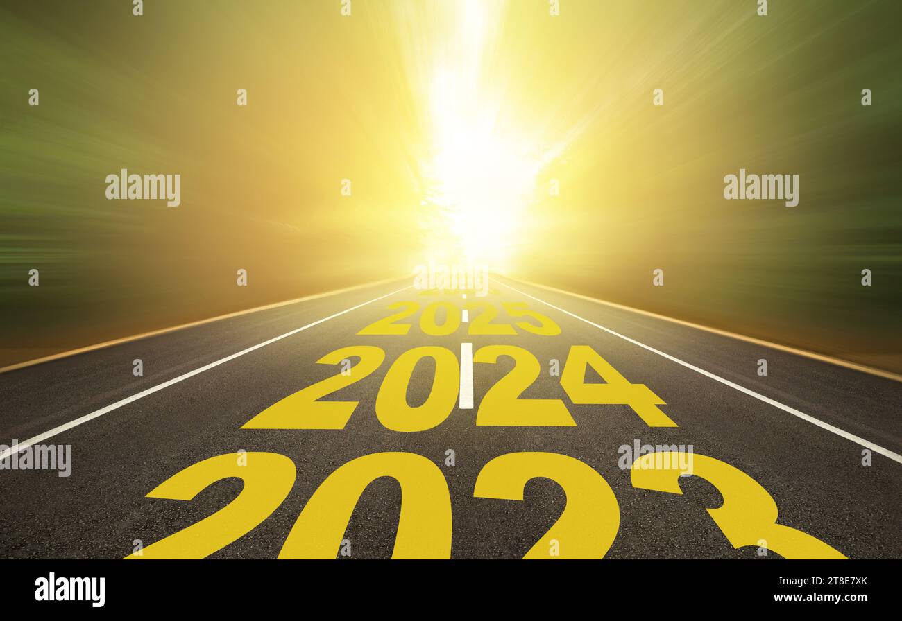The word 2024 to 2028 written on highway road in the middle of empty asphalt road at golden sunrise. New year 2024 concept. Stock Photo