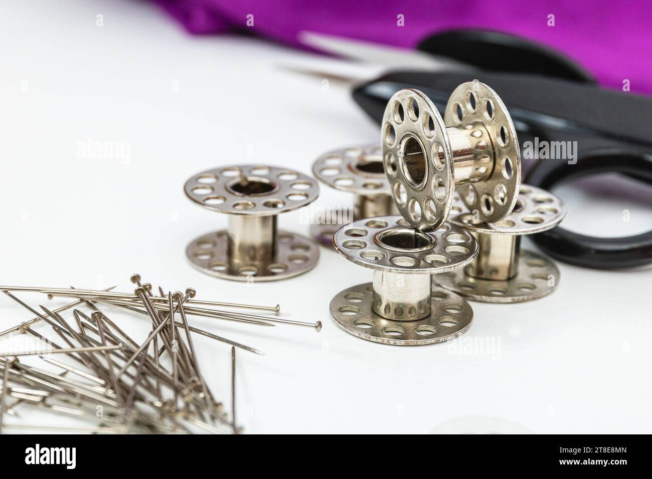Horizontal photo, bobbins and sewing material presented on a white table, for manual textile works. Stock Photo