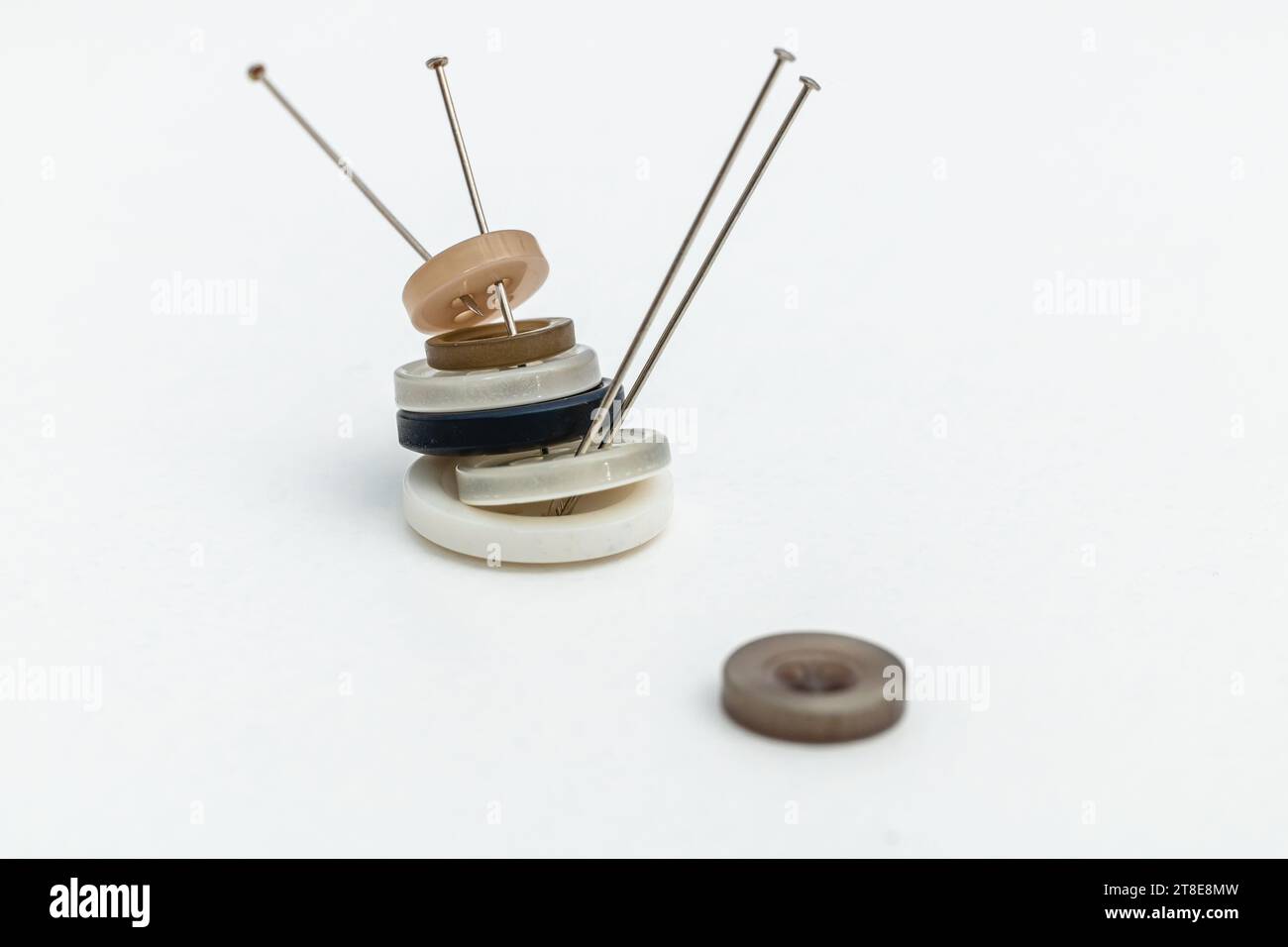 Horizontal photo, buttons stacked with pins, on white background, copy space. Concept hobbies and handicrafts. Stock Photo