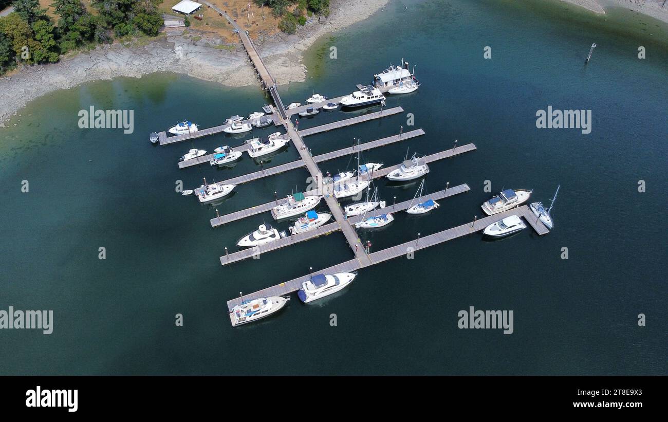 Sailing boat, motorboats, dock and little island. Little harbour from the top. Aerial point of view. Dron view Stock Photo