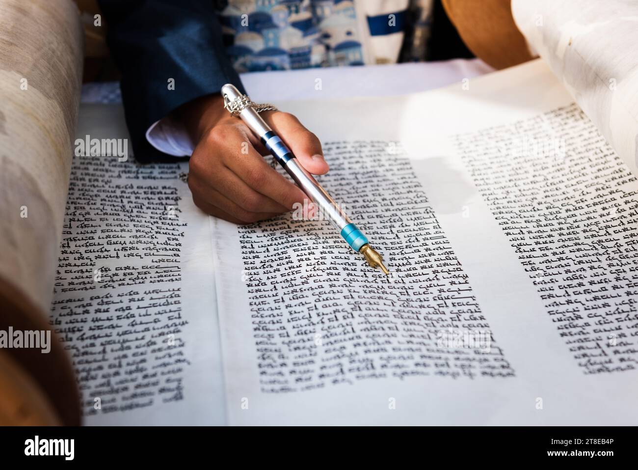 Closeup of a hand holding a yad or pointer to guide the reader through the Hebrew text of the Jewish Torah. Stock Photo