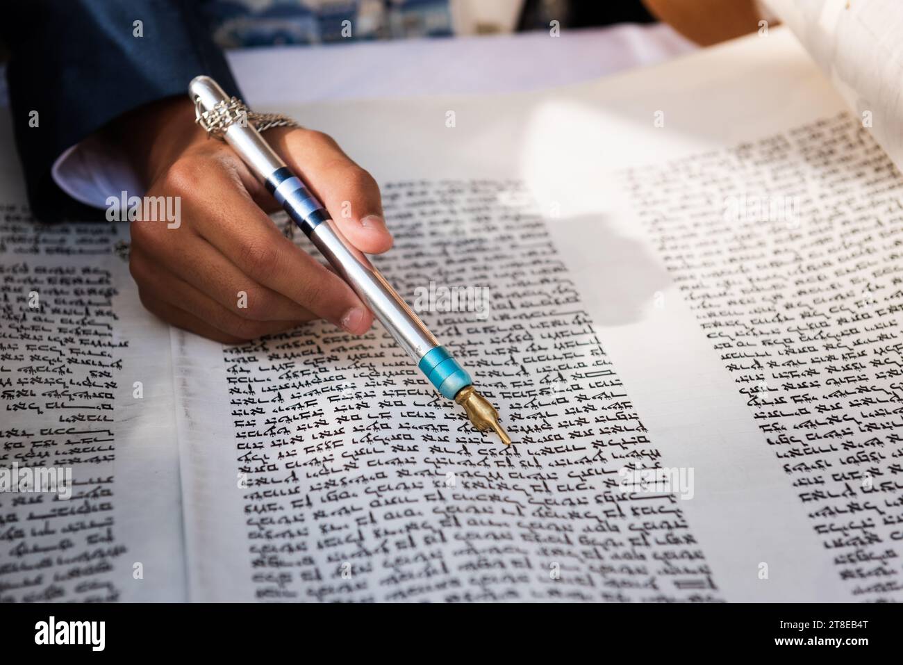 Closeup of a hand holding a yad or pointer to guide the reader through the Hebrew text of the Jewish Torah. Stock Photo