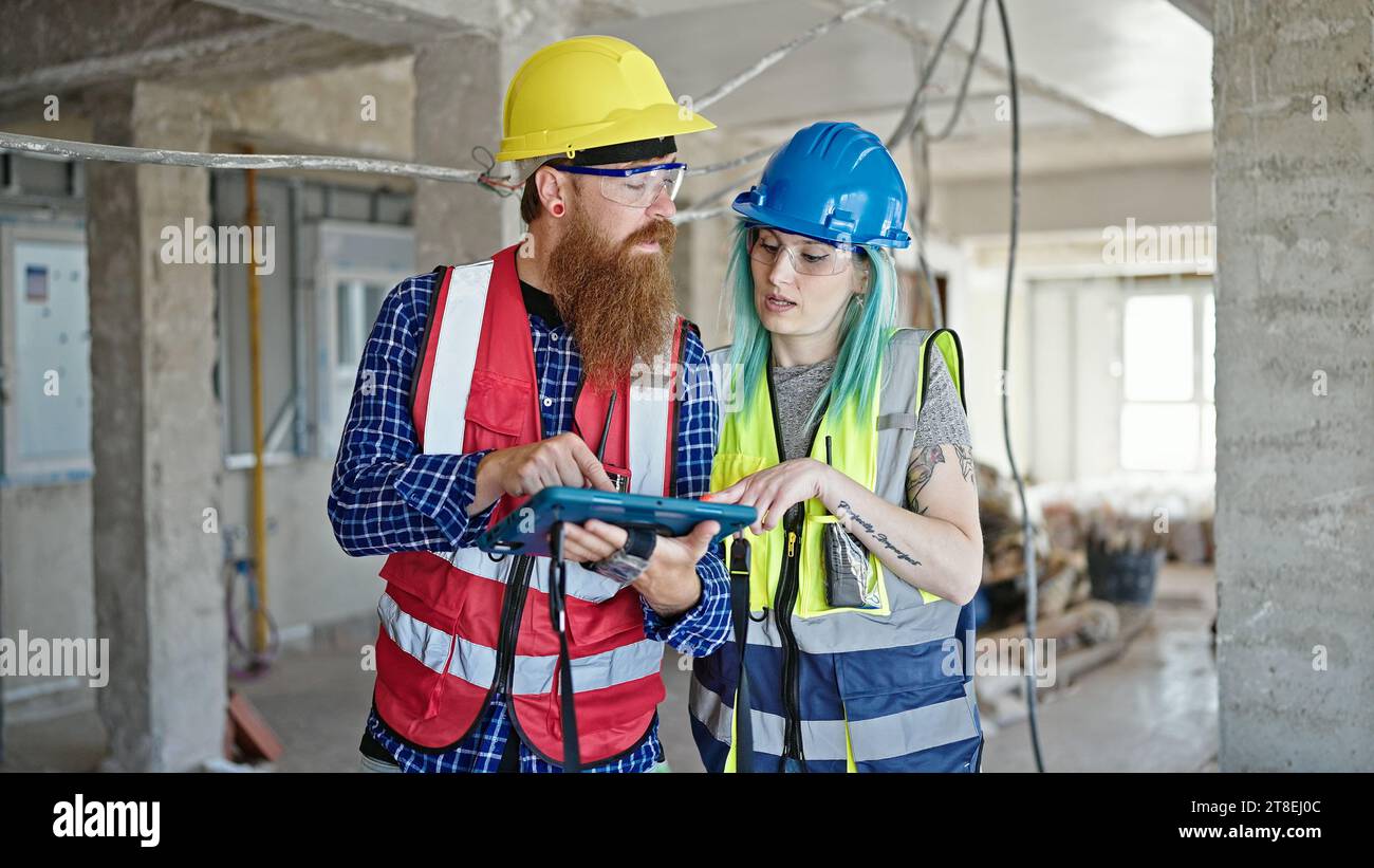 Man and woman builders using touchpad working at construction site Stock Photo