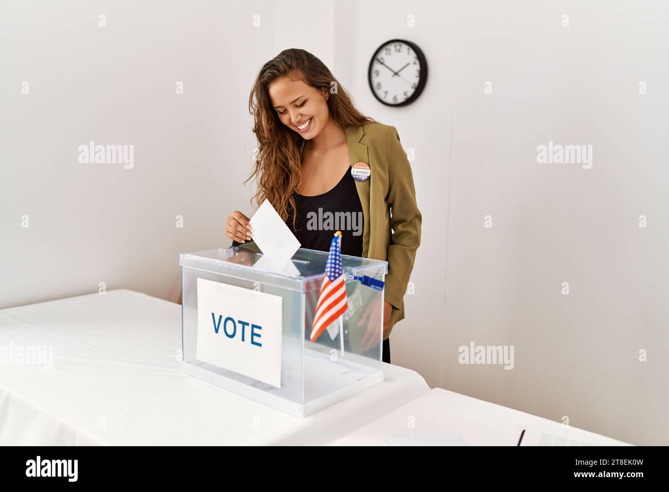 Young beautiful hispanic woman electoral table president putting vote in box at electoral college Stock Photo