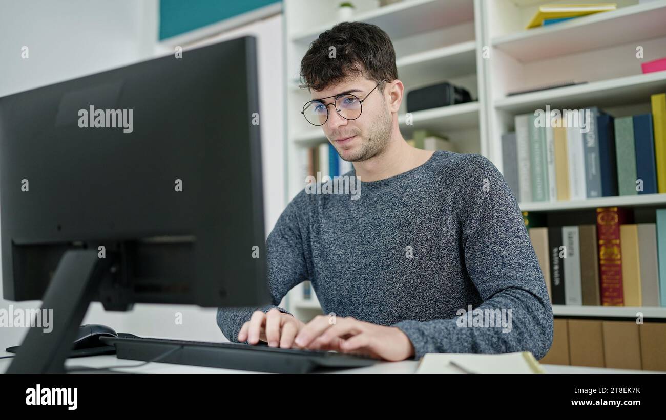 Hispanic Man Using Computer Young hispanic man student using computer studying at library ...