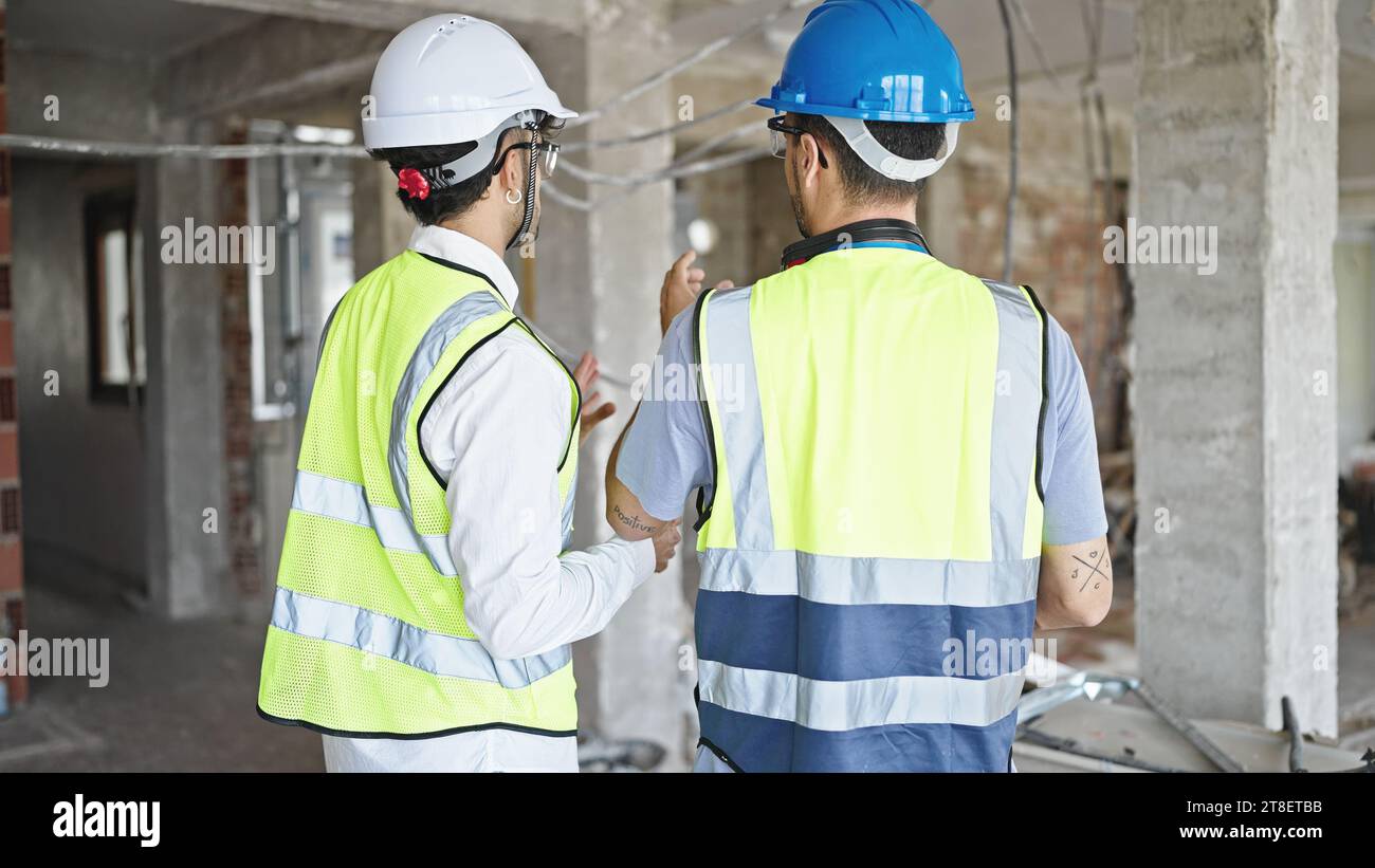 Two men builders standing backwards speaking at construction site Stock Photo