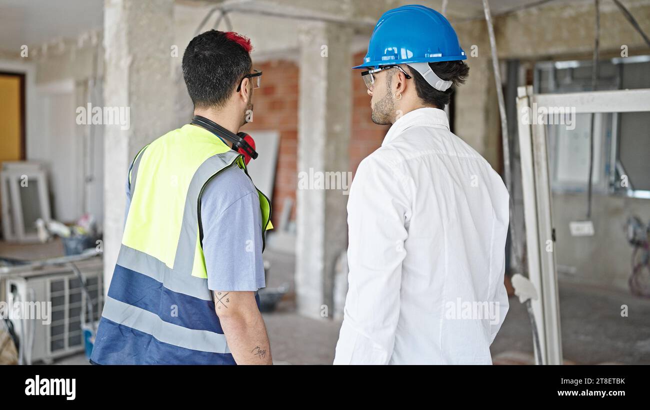 Two men builder and architect standing together backwards at construction site Stock Photo