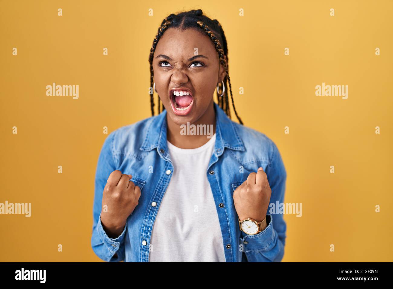 African american woman with braids standing over yellow background ...