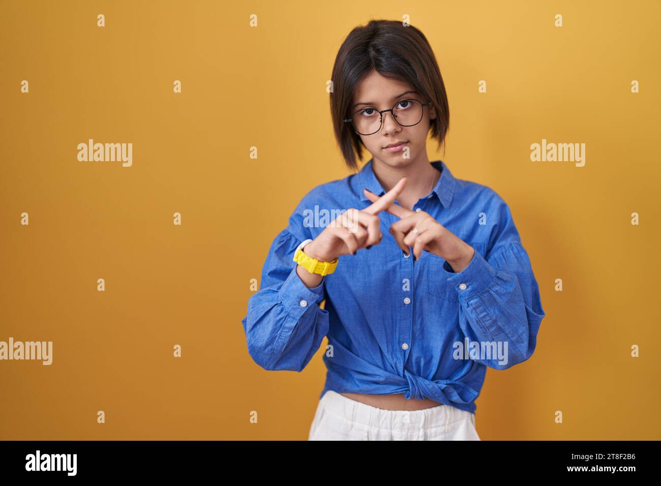 Young girl standing over yellow background rejection expression ...