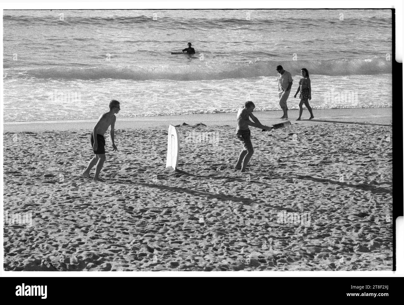 Teenagers play cricket on the beautiful sandy beach at Gwynver Beach at Sennen with a surf board as the stumps in Cornwall, England, August 2000. Picture: ROB WATKINS Stock Photo