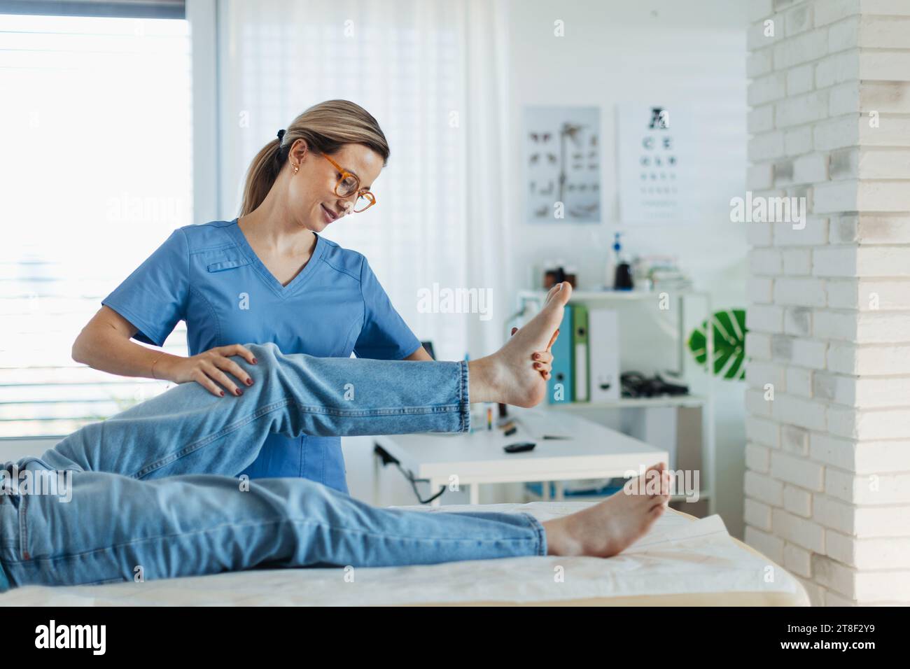 Physiotherapist doing manual therapy, exercise with teenage boy's knee, rehabilitation