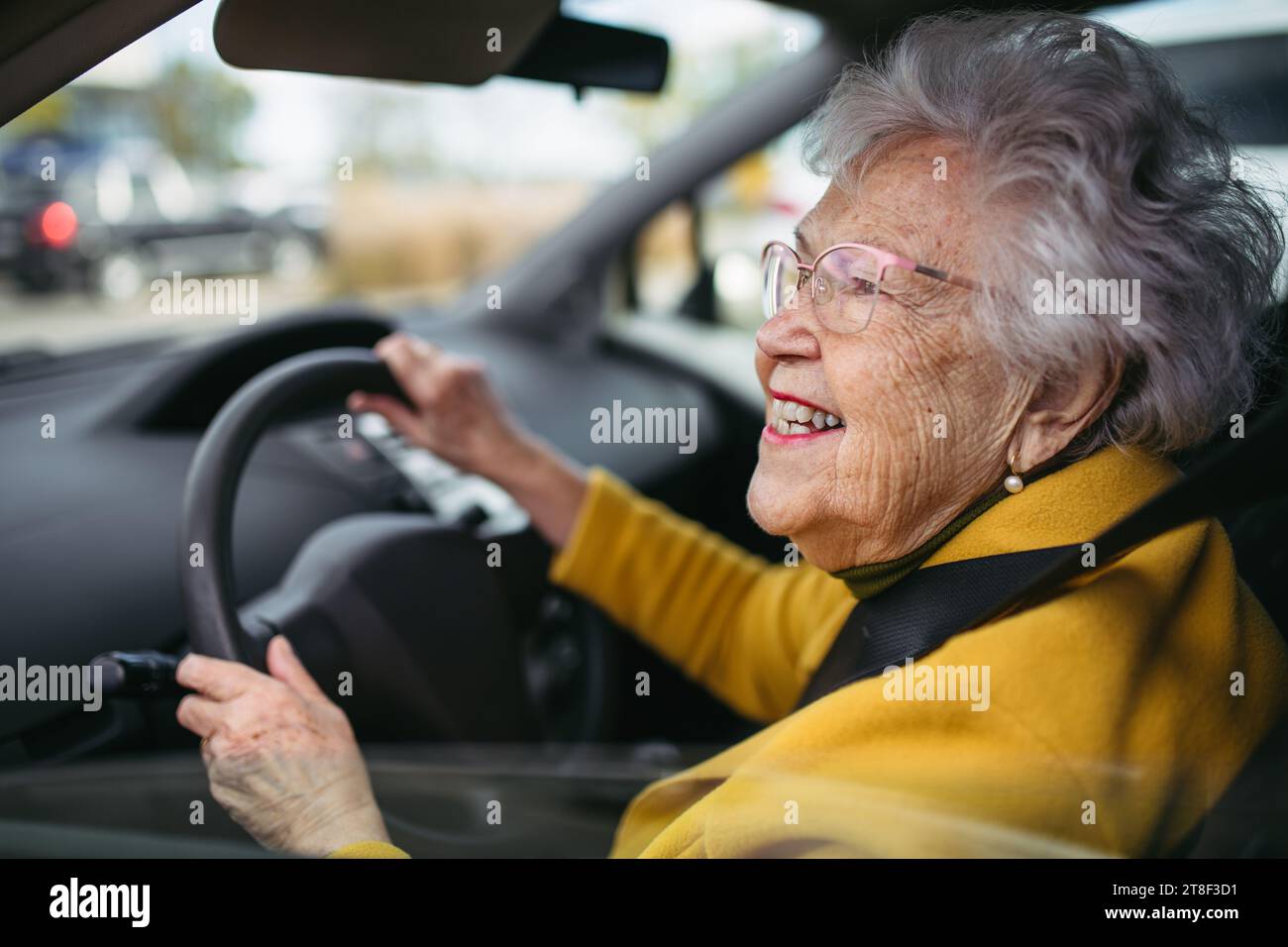 Happy senior woman driving car alone, enjoying car ride. Safe driving