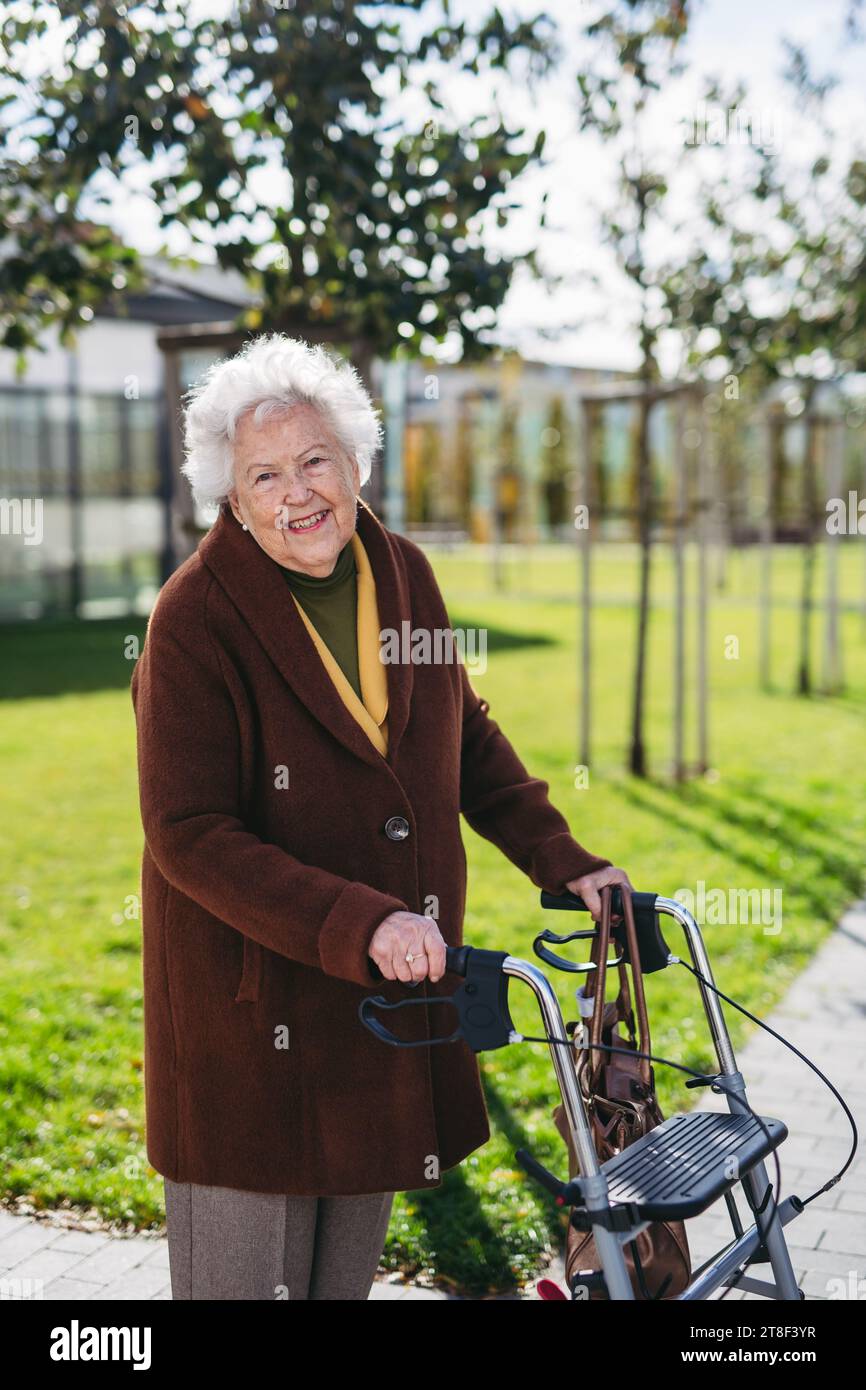 Senior woman with a mobility walker walking on city streets during ...