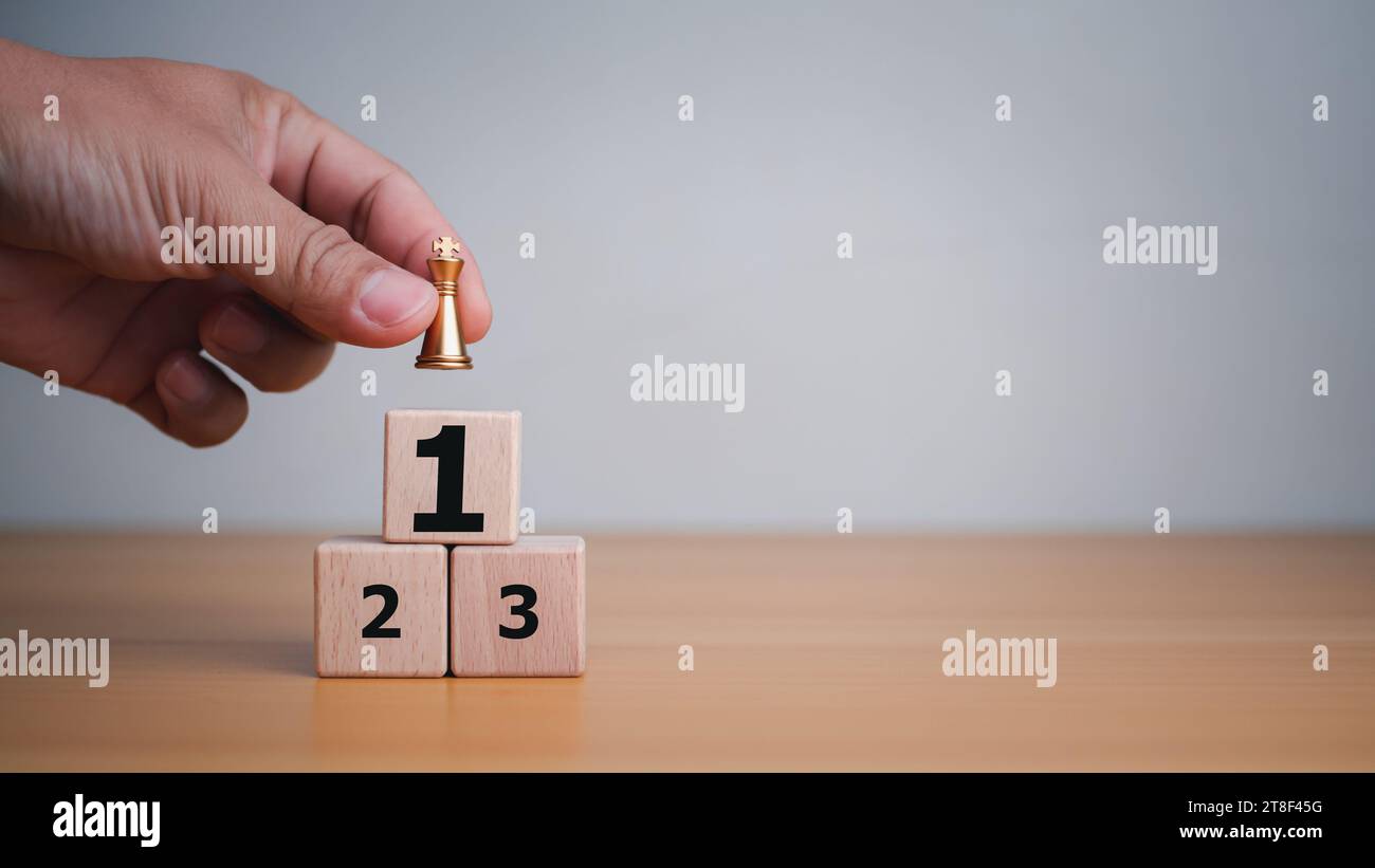 Businessman hand holding a king placed on the topmost layer of wood. It represents the concept of competition and strategic adjustments for competitor Stock Photo