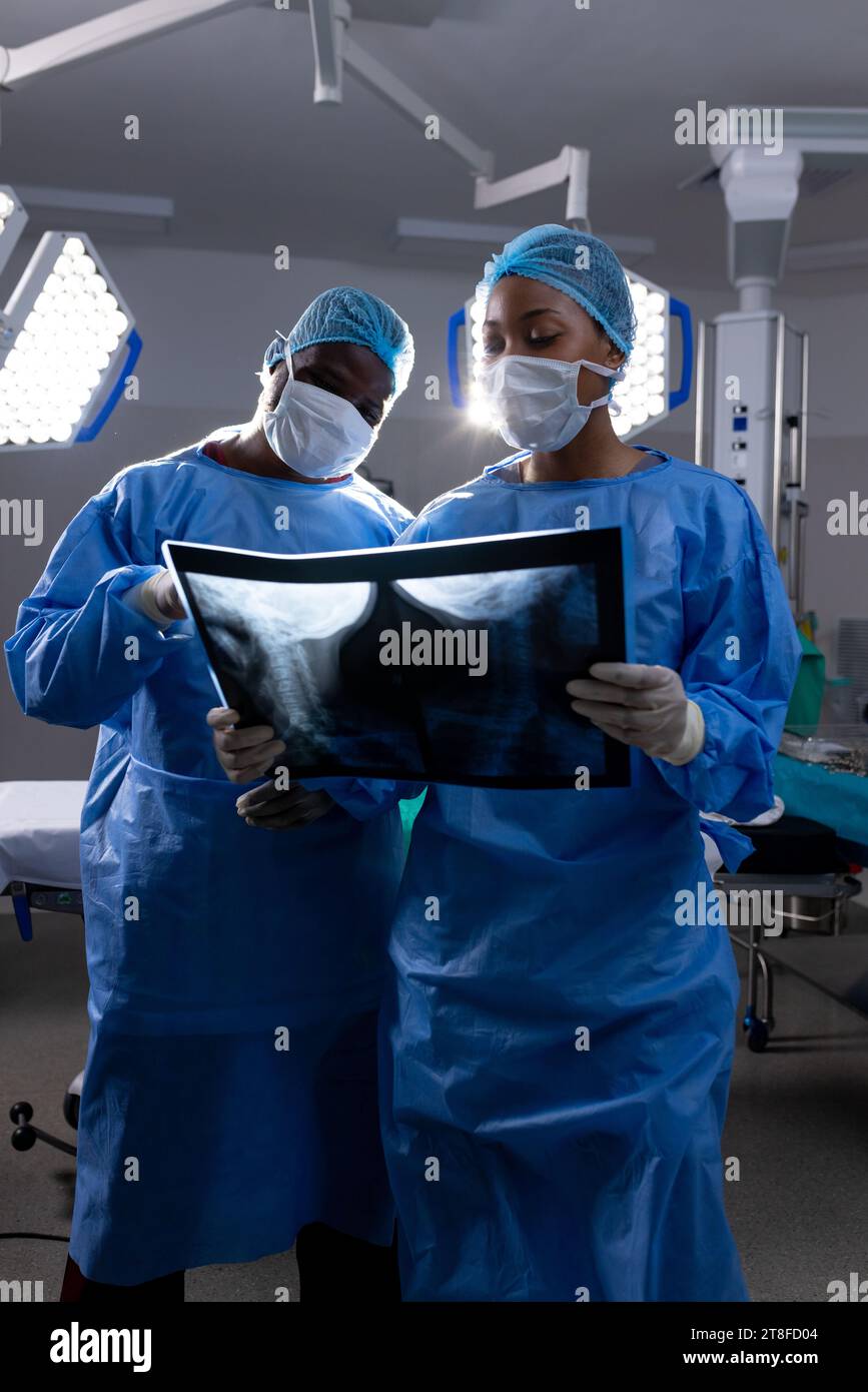 African american male and female doctors with face masks looking at xrays in hospital Stock