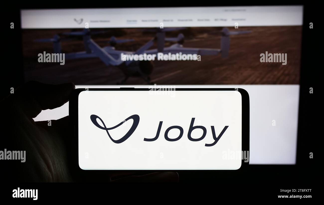 Person holding smartphone with logo of US eVTOL aircraft company Joby Aviation in front of website. Focus on phone display. Stock Photo