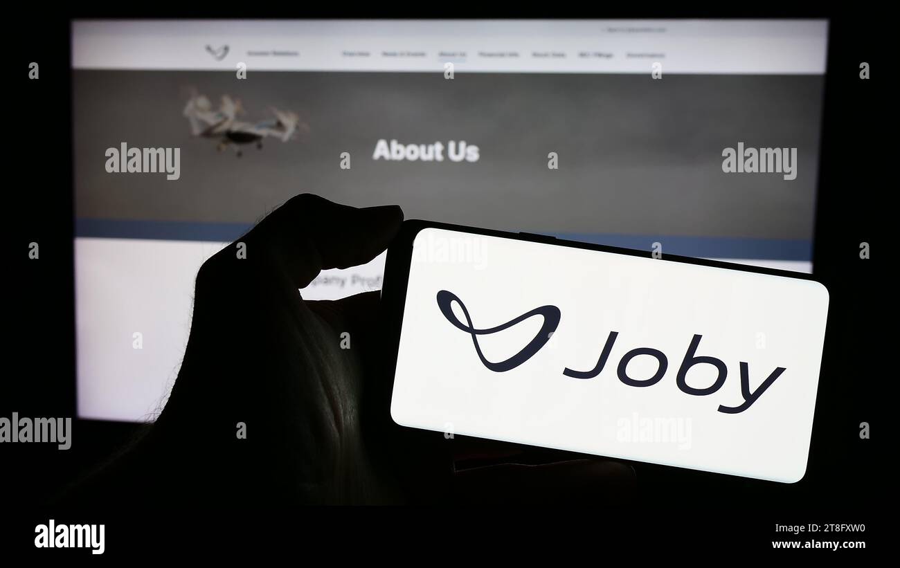 Person holding cellphone with logo of US eVTOL aircraft company Joby Aviation in front of business webpage. Focus on phone display. Stock Photo