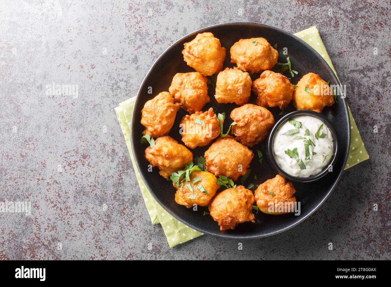 Southern Hush Puppies are light and flakey cornmeal dough that is fried golden brown on the outside and soft on the inside closeup on the plate on the Stock Photo