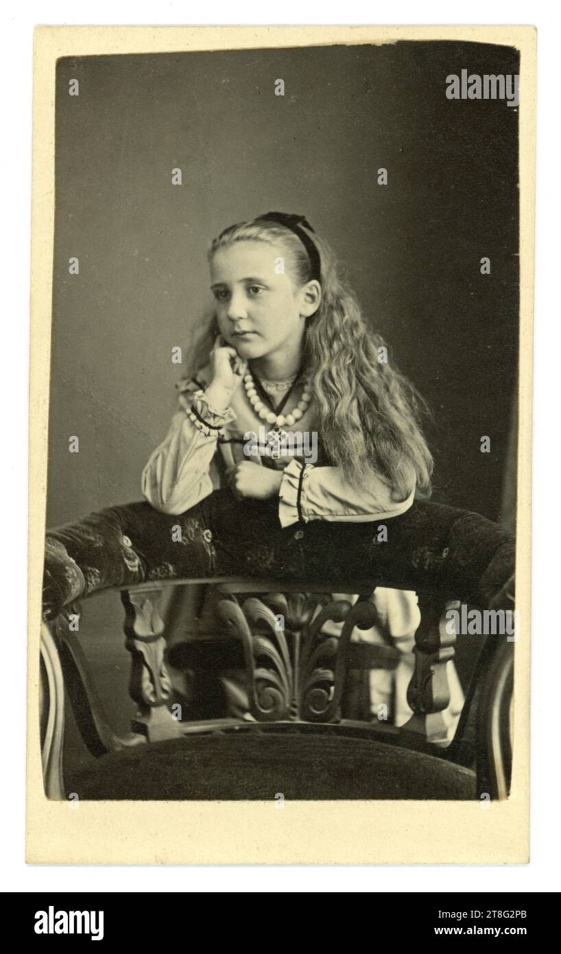 Original Victorian CDV of young Alice in Wonderland look-alike girl. She wears a necklace of white beads and a cross. From the studio of John Waller, Pier Portrait Rooms, Whitby, Yorkshire, England, U.K. Circa 1865. Stock Photo