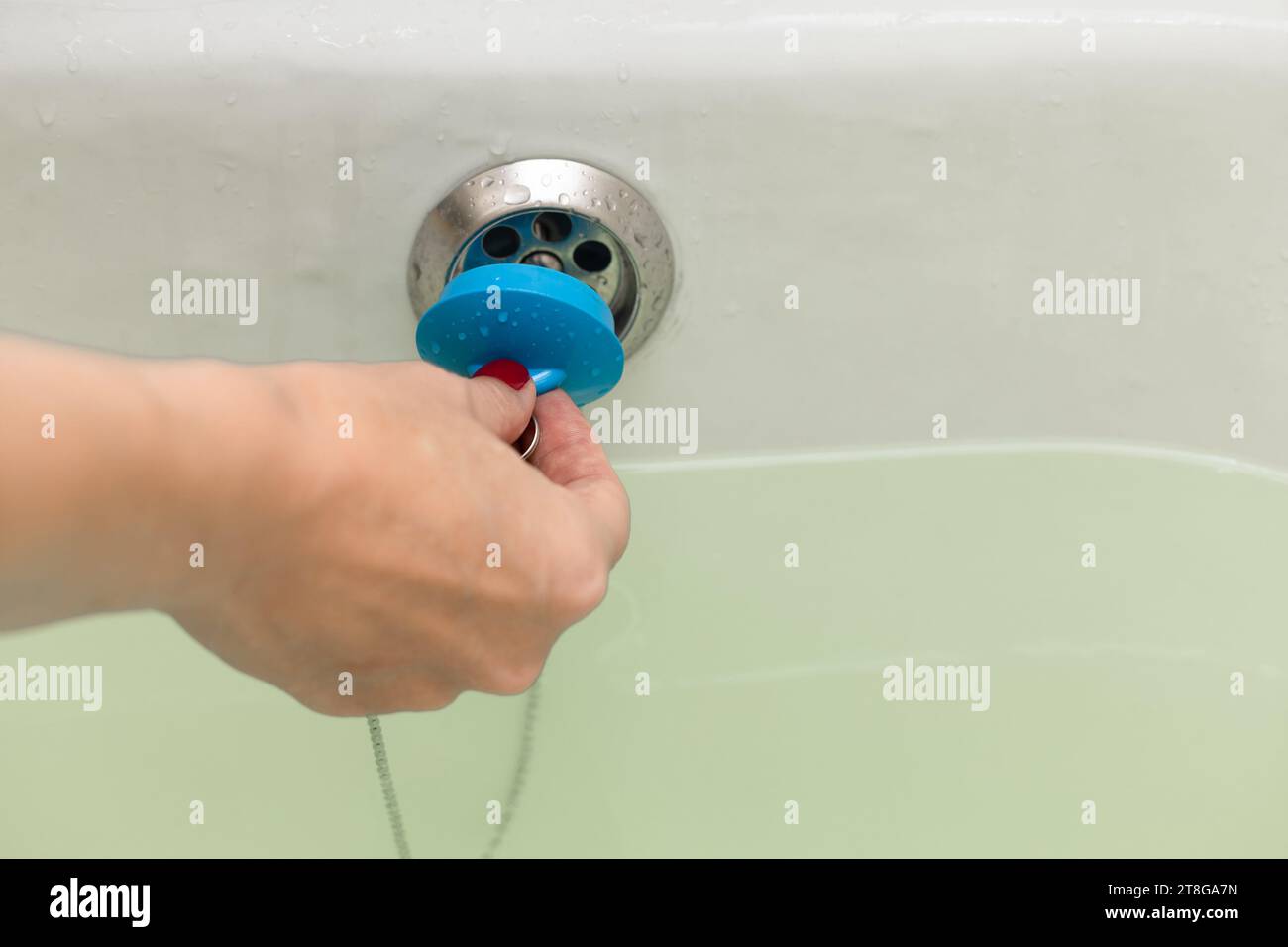 woman's hand closes the drain hole in the bathroom. drain hole in the