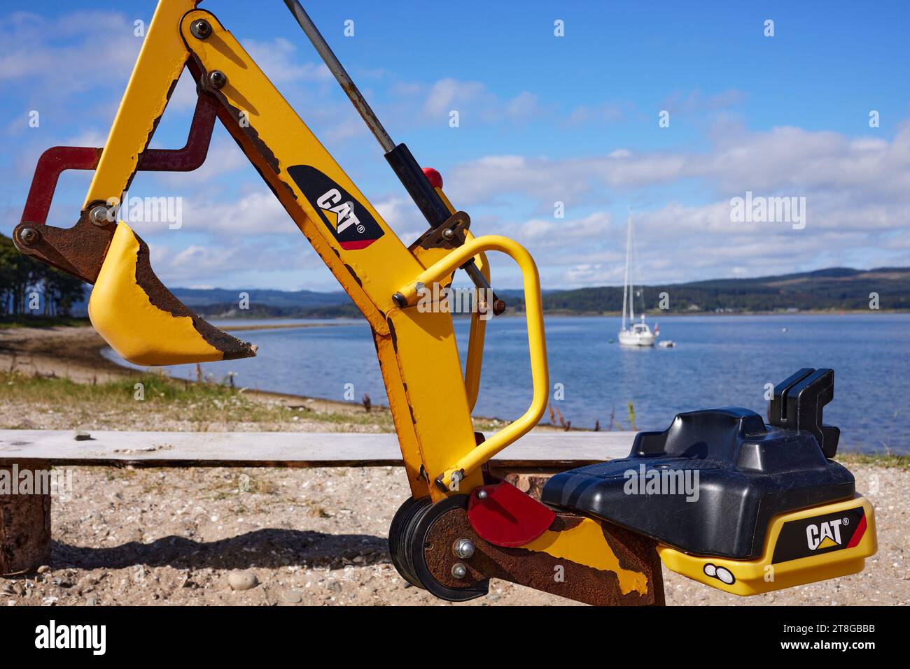 A close-up view of a toy CAT digger on the beach at Otter Ferry. Argyll Stock Photo