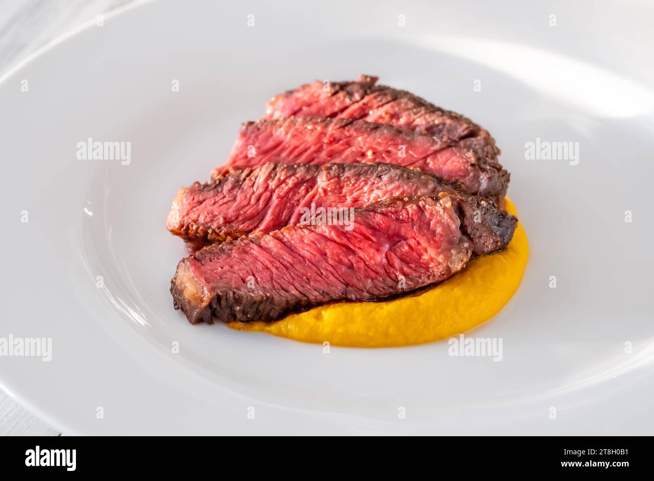 Sliced rib eye steak garnished with carrot garlic cream Stock Photo
