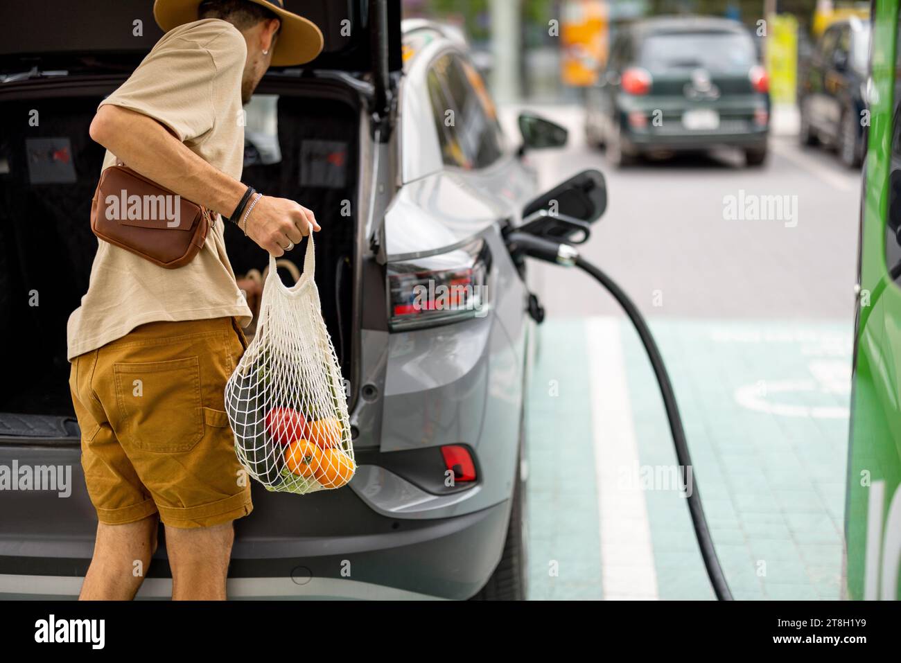Man charging electric car while shopping Stock Photo
