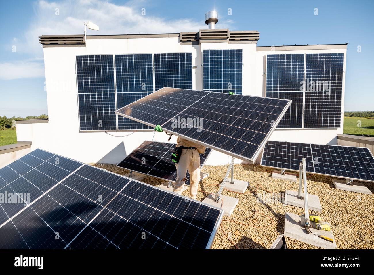 Man installing solar panels on a rooftop Stock Photo