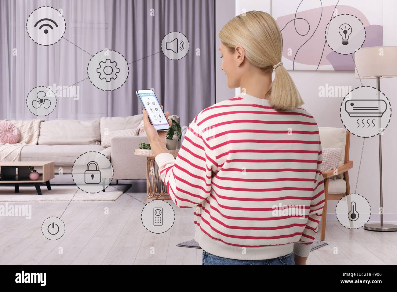 Woman using smart home control system via application on mobile phone indoors. Different icons around her Stock Photo