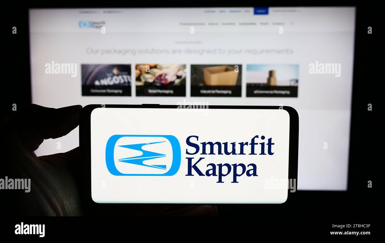 Person holding cellphone with logo of Irish packaging company Smurfit Kappa Group plc in front of business webpage. Focus on phone display. Stock Photo