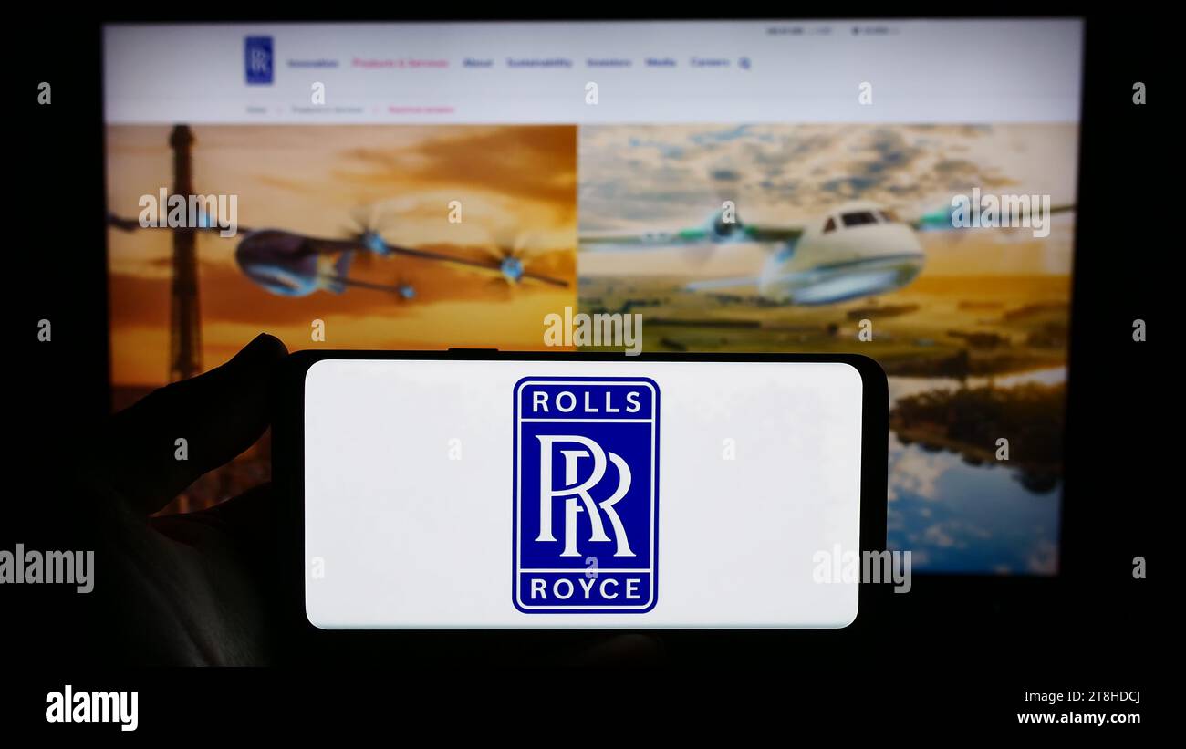 Person holding smartphone with logo of British aerospace company Rolls-Royce Holdings plc in front of website. Focus on phone display. Stock Photo