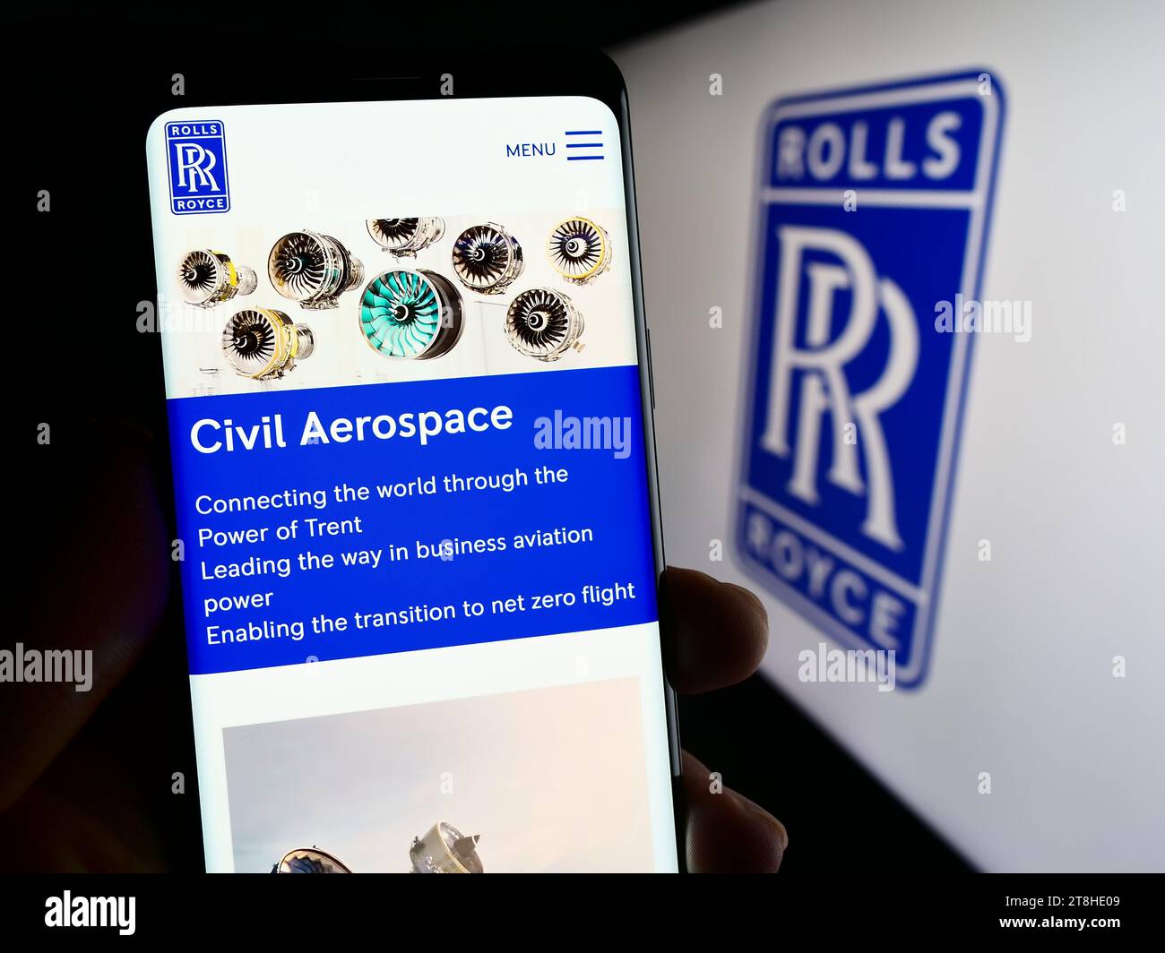 Person holding cellphone with web page of British aerospace company Rolls-Royce Holdings plc in front of logo. Focus on center of phone display. Stock Photo