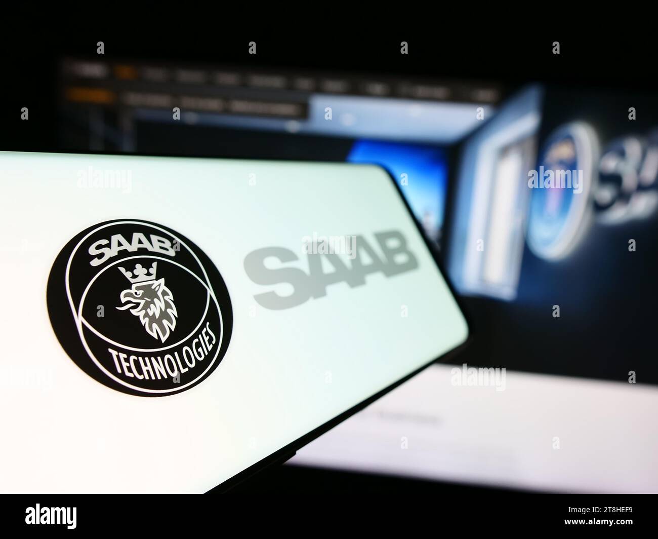 Cellphone with logo of Swedish aerospace and defense company Saab AB in front of business website. Focus on left of phone display. Stock Photo