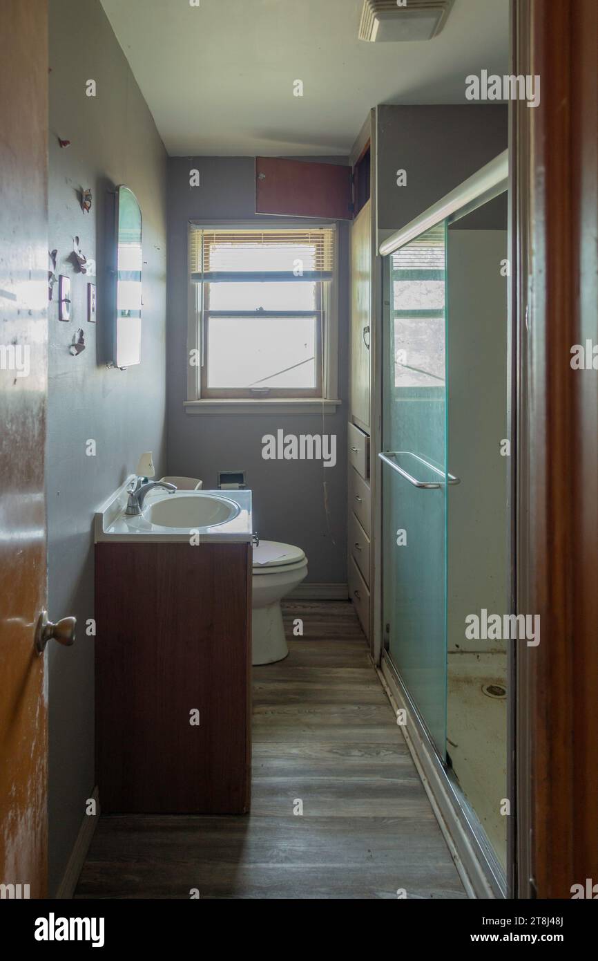 Narrow bathroom or loo in an old farmhouse for sale, needing a remodel. Kansas, USA. Stock Photo
