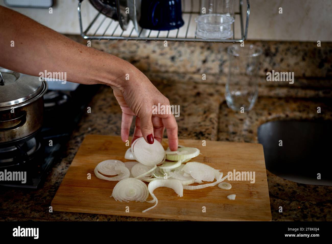 https://c8.alamy.com/comp/2T8K0J4/hand-holding-sliced-onions-on-a-cutting-board-food-seasoning-2T8K0J4.jpg