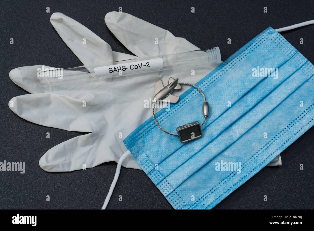 latex glove, test tubule, mask, and luggage tag with plane, flight voyage under Corona conditions Stock Photo