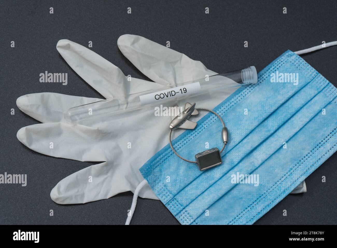 latex glove, test tubule, mask, and luggage tag with plane, flight voyage under Corona conditions Stock Photo