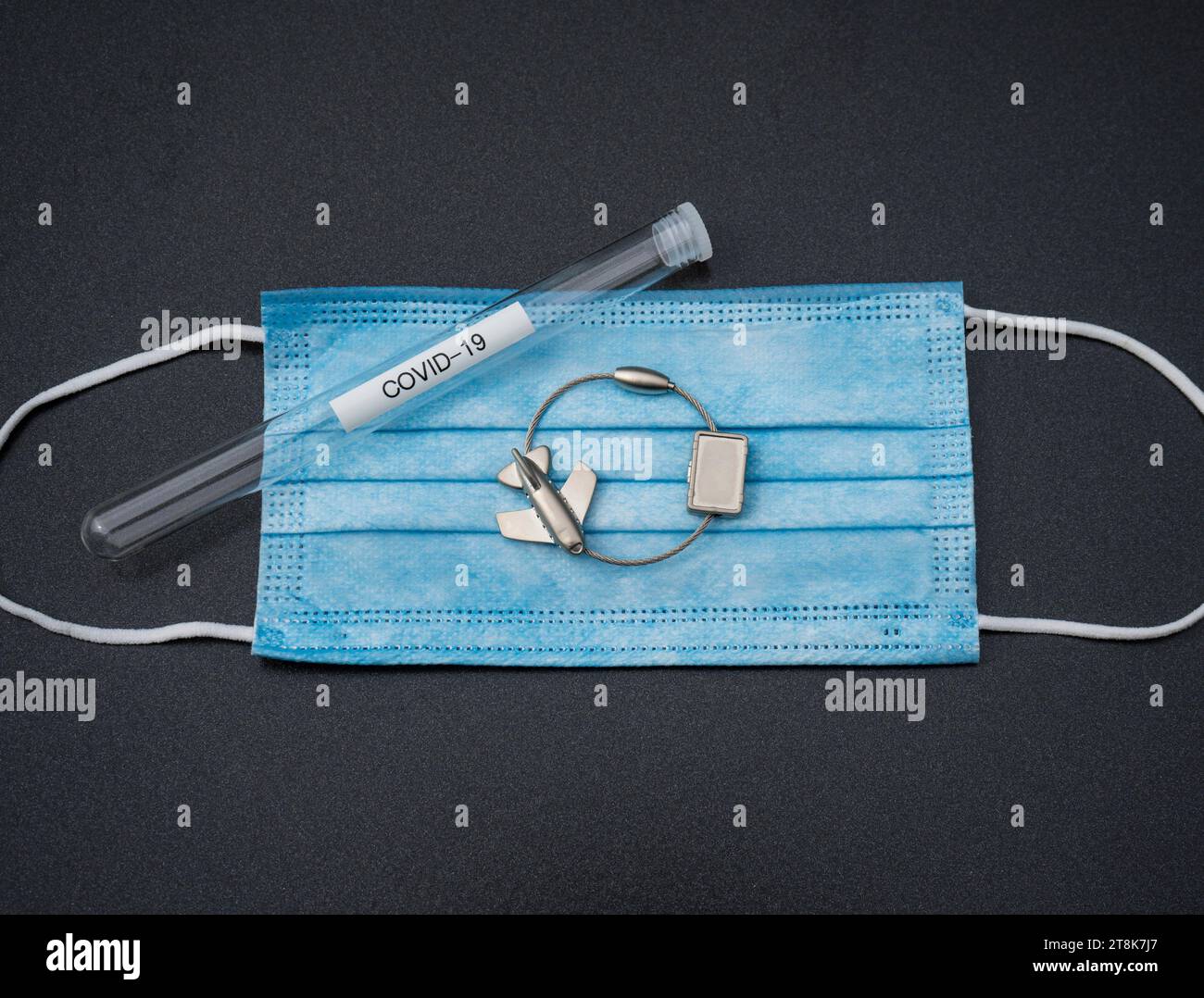 face mask, test tubule, and luggage tag with plane, flight voyage under Corona conditions Stock