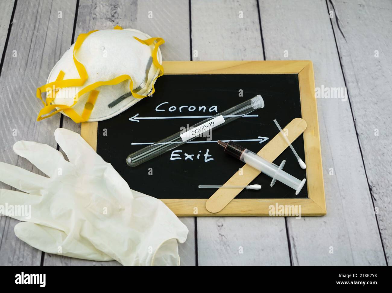 mask, latex gloves, syringe, spatula and test tubule on blackboard with arrows right and left, Corona and exit Stock Photo