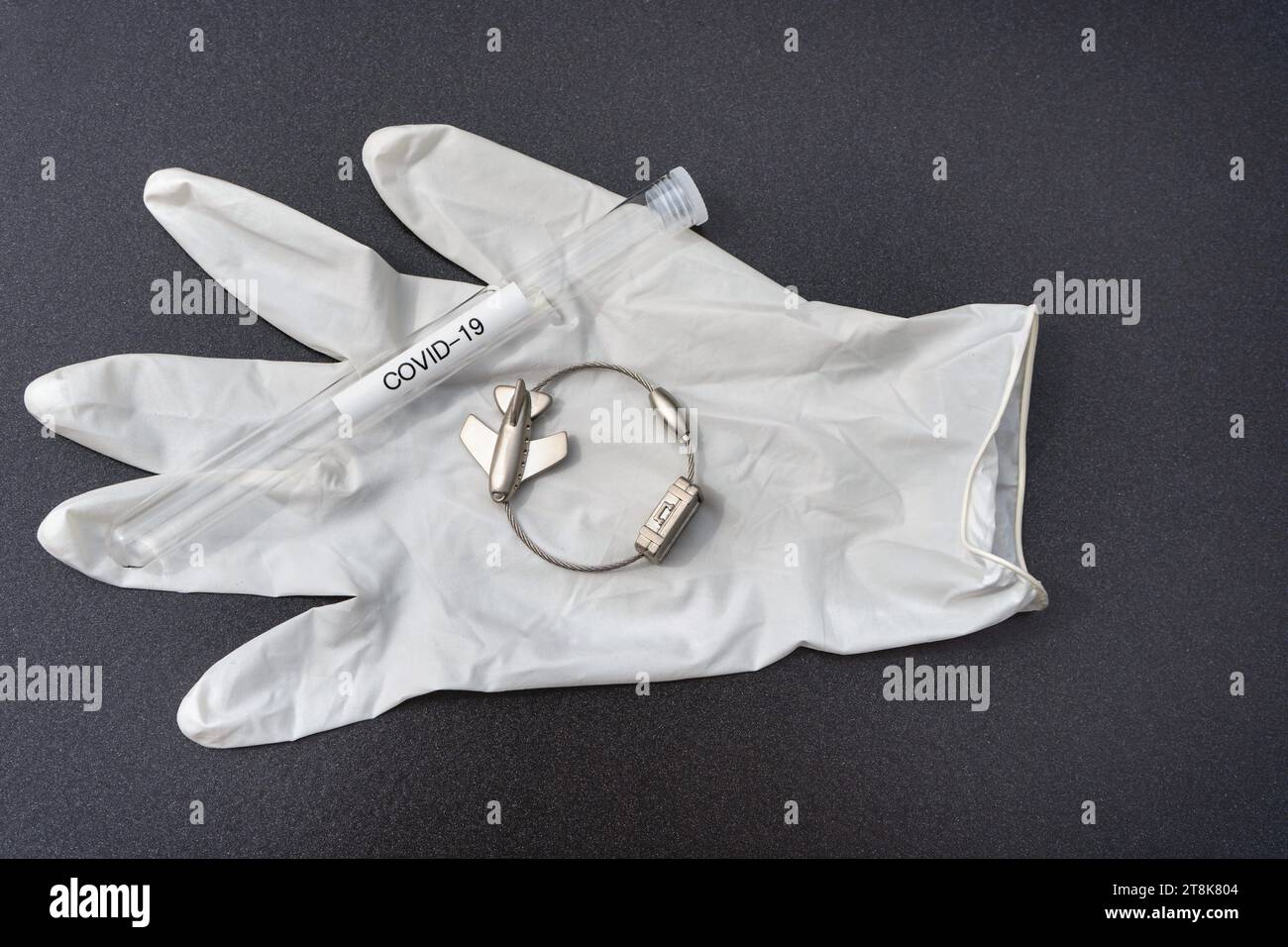 latex glove, test tubule, and luggage tag with plane, flight voyage under Corona conditions Stock Photo