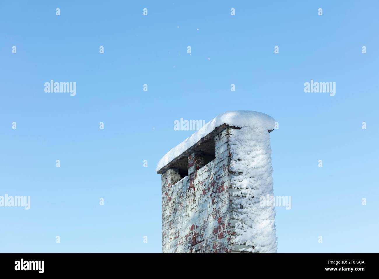 Snow on brick chimney against blue sky Stock Photo