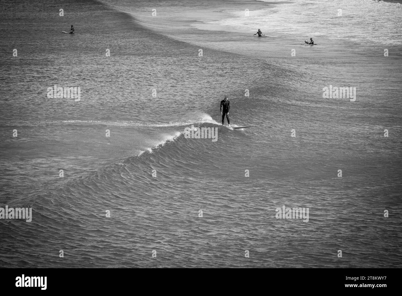 A surfer stands upright on a small wave at Maroubra Beach. Stock Photo
